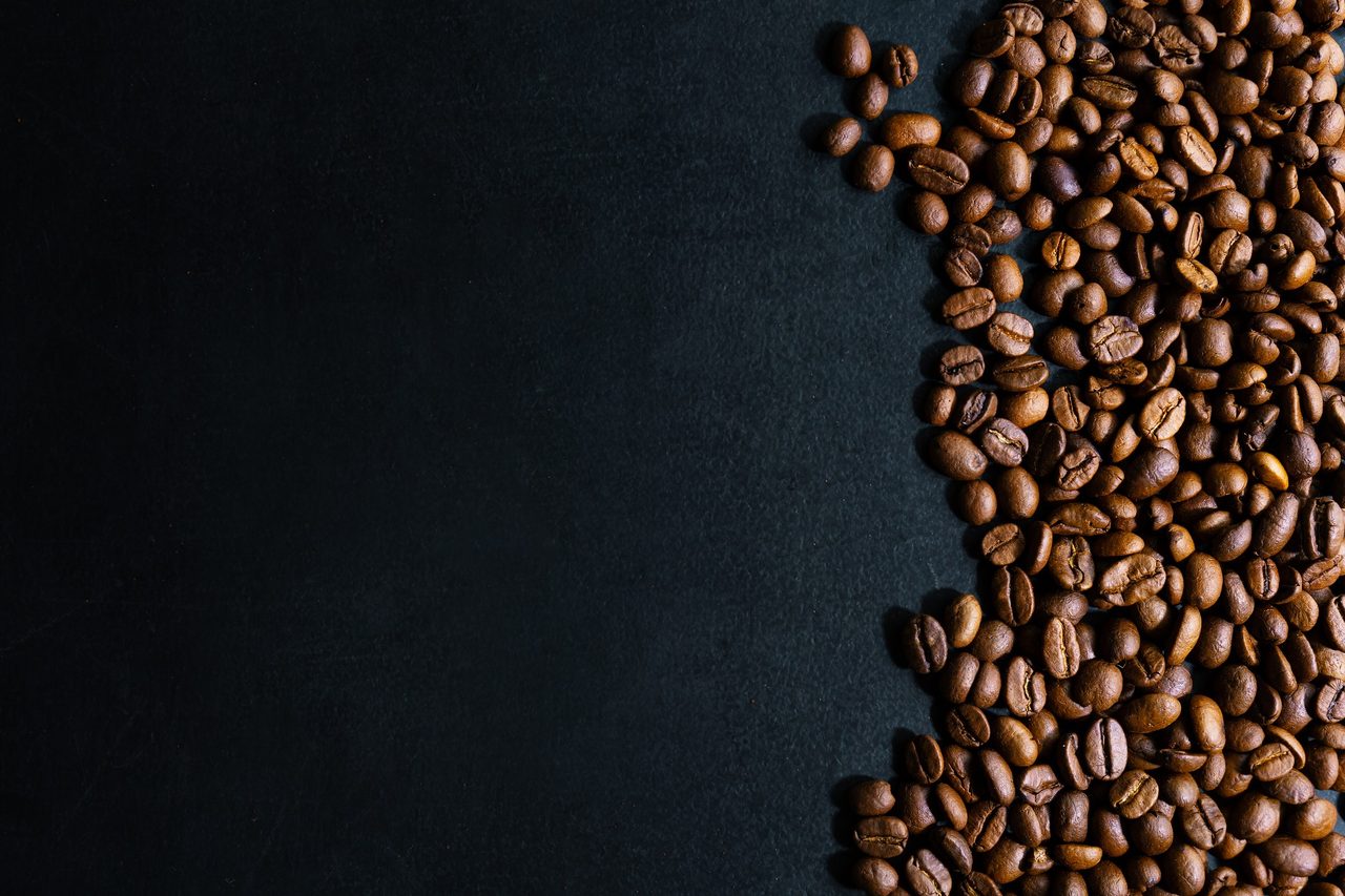 Granos de café sobre una superficie oscura.